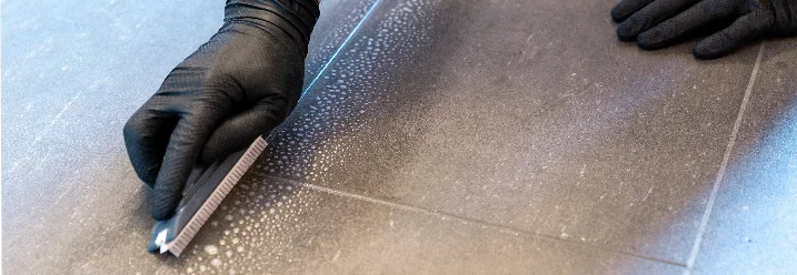 Person reinigt Fliesen mit Fugenbürste